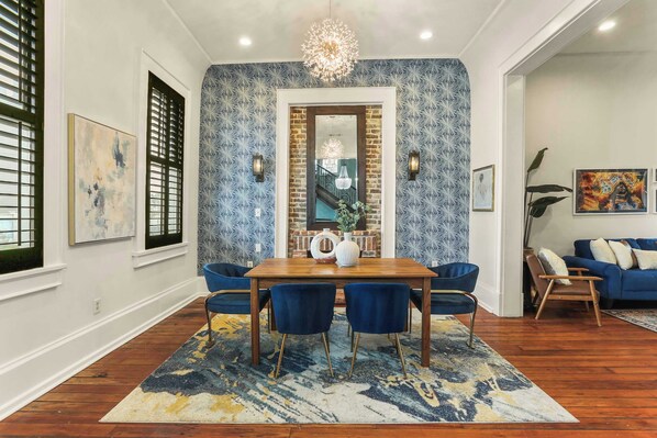 A dining area with a wooden table, blue chairs, and a patterned rug.