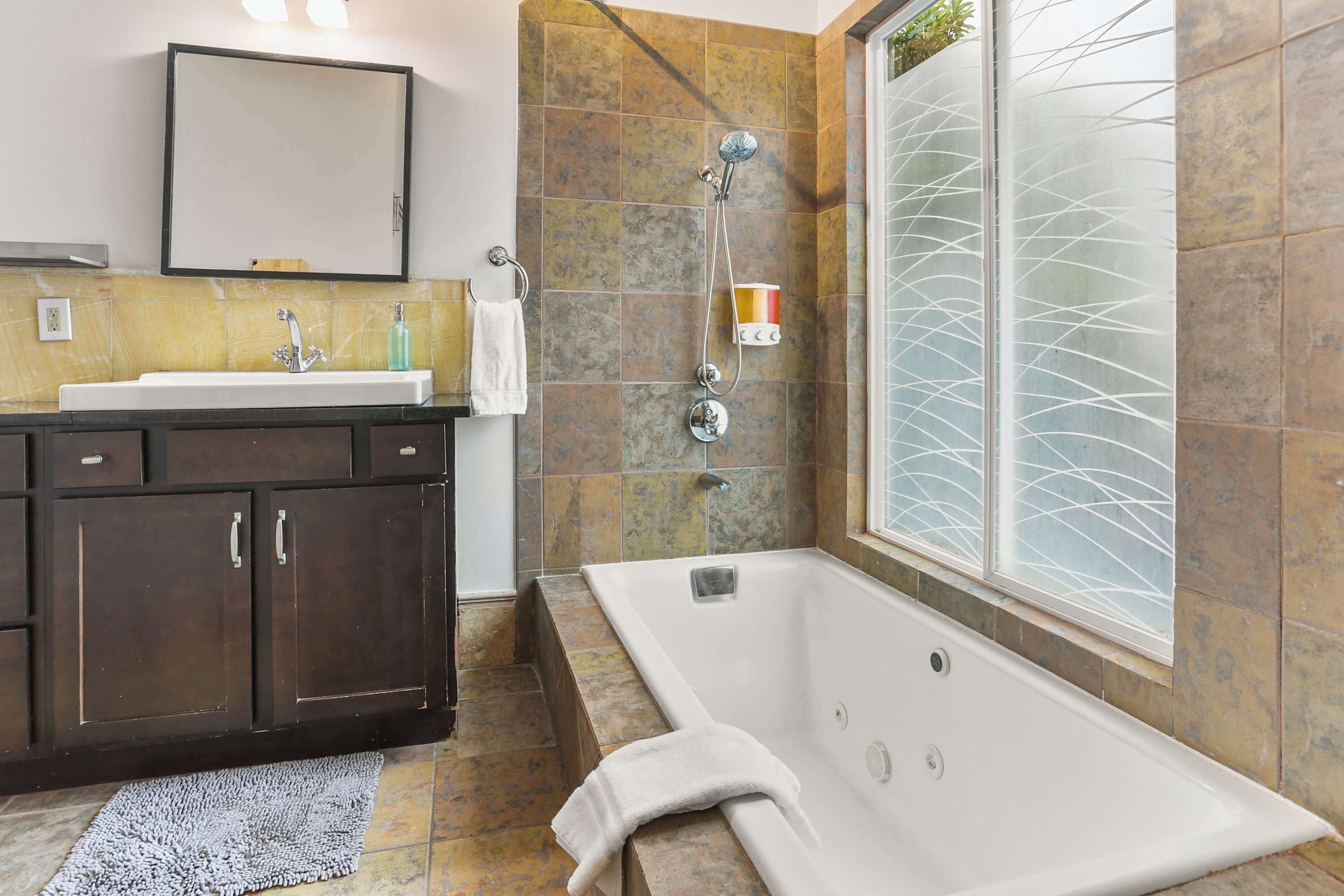 A bathroom with a bathtub, a sink, and a mirror.