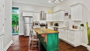 A modern kitchen with white cabinets, a wooden island, and a stainless steel refrigerator. - Designer's Dream! 3 bed/2.5 bath (New Orleans)