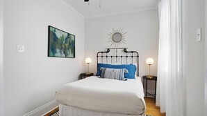Ein Schlafzimmer mit einem Bett, zwei Nachttischen, einem Wandspiegel und einem Gemälde.