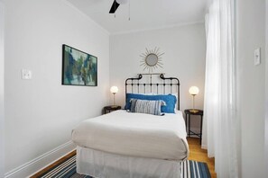 Ein Schlafzimmer mit einem Bett, zwei Nachttischen, einem Wandspiegel und einem Gemälde.