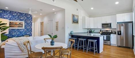 A modern kitchen with white cabinets, stainless steel appliances, and a wooden island.
