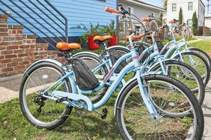 Una hilera de bicicletas azul claro con asientos naranja y bolsas negras, estacionadas sobre césped.