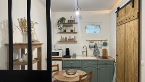 A compact kitchen with a wooden table, a sink, and a hanging light fixture. - Studio Normand (Dives-sur-Mer)