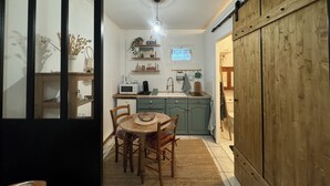 A kitchen with a dining table, chairs, a microwave, and a sink. - Studio Normand (Dives-sur-Mer)