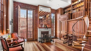 Una habitación amplia con chimenea, piso de madera y una escalera en espiral.