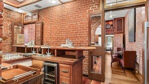 Una cocina con pared de ladrillo, armarios de madera y pileta de acero inoxidable.