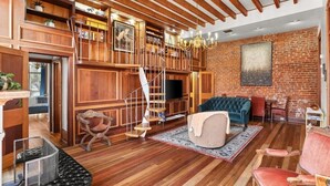 Un salón amplio con una escalera de madera, un televisor y una zona de estar confortable.