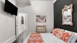 Una camera da letto moderna con un letto, una TV, opere d'arte e uno specchio.