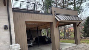 Un garage moderne doté d’une entrée abritée, d’un banc en béton et contenant un véhicule à l’intérieur.