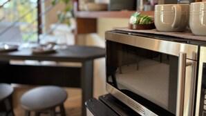 Une cuisine équipée d’un four à micro-ondes, d’une machine à café et d’une petite plante posée sur le plan de travail.