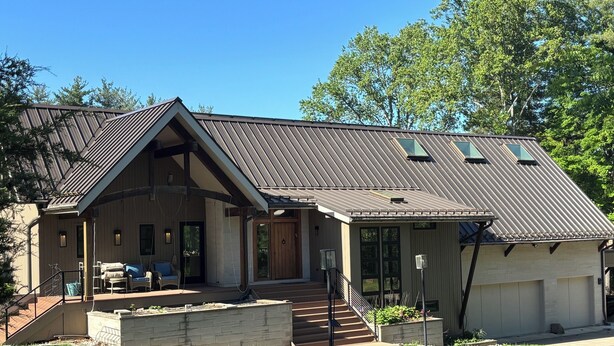 Une maison à deux étages avec un porche abrité, un garage et une cour aménagée.