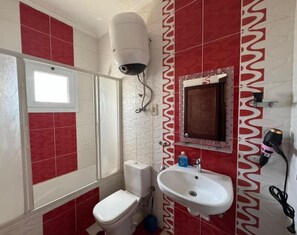 Bathroom features a toilet, sink, and shower with a glass door.