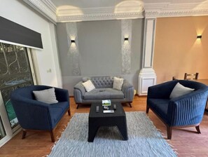 Relax in this stylish living room with a grey sofa, tufted armchairs, and a woven coffee table.