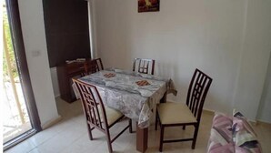 Comedor con una mesa cubierta por un mantel estampado, rodeado de sillas de madera.