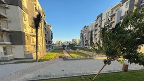A residential area with modern apartment buildings, paved pathways, and green spaces. - 803 . Spacious 3BR Apt., 2 Baths, Gated Community (Al Sheikh Zayed)