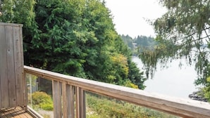 Ein Holzdeck mit Glasgeländer, das auf einen See mit üppiger, grüner Vegetation blickt.