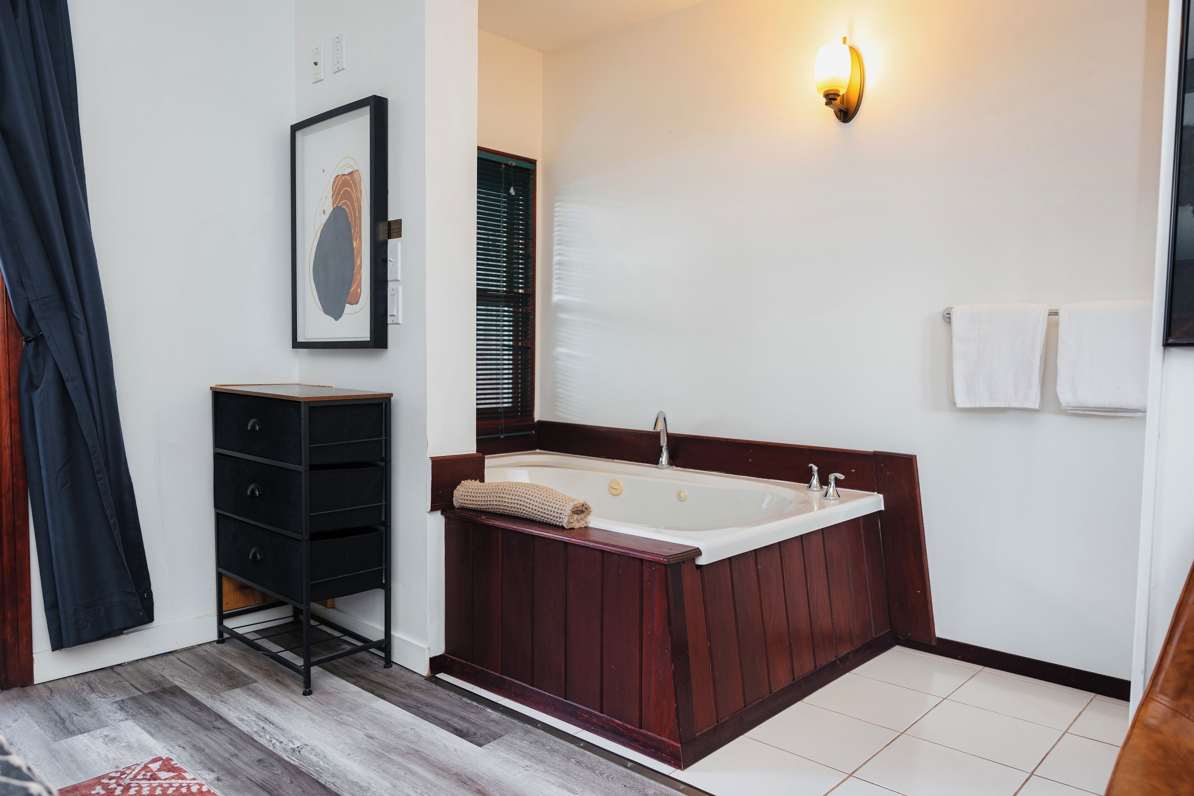 Ein modernes Badezimmer mit einer Holzbadewanne, einem kleinen Waschbecken und einem Handtuchhalter.