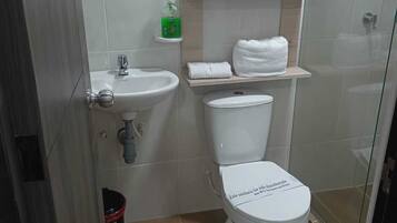 A compact bathroom with a toilet, sink, and glass shower enclosure.