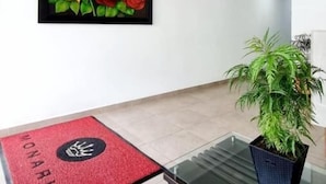 Een receptiegedeelte met een rode deurmat, een glazen tafel en een potplant.