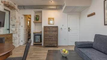 Una sala moderna con una pared de acento de piedra, una mesa de comedor de madera, un sofá gris y una mesa baja con fruta.