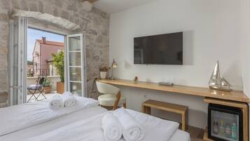 Habitación de hotel con dos camas, televisión, una mesita de noche con lámpara, un modelo de barco y un minibar.