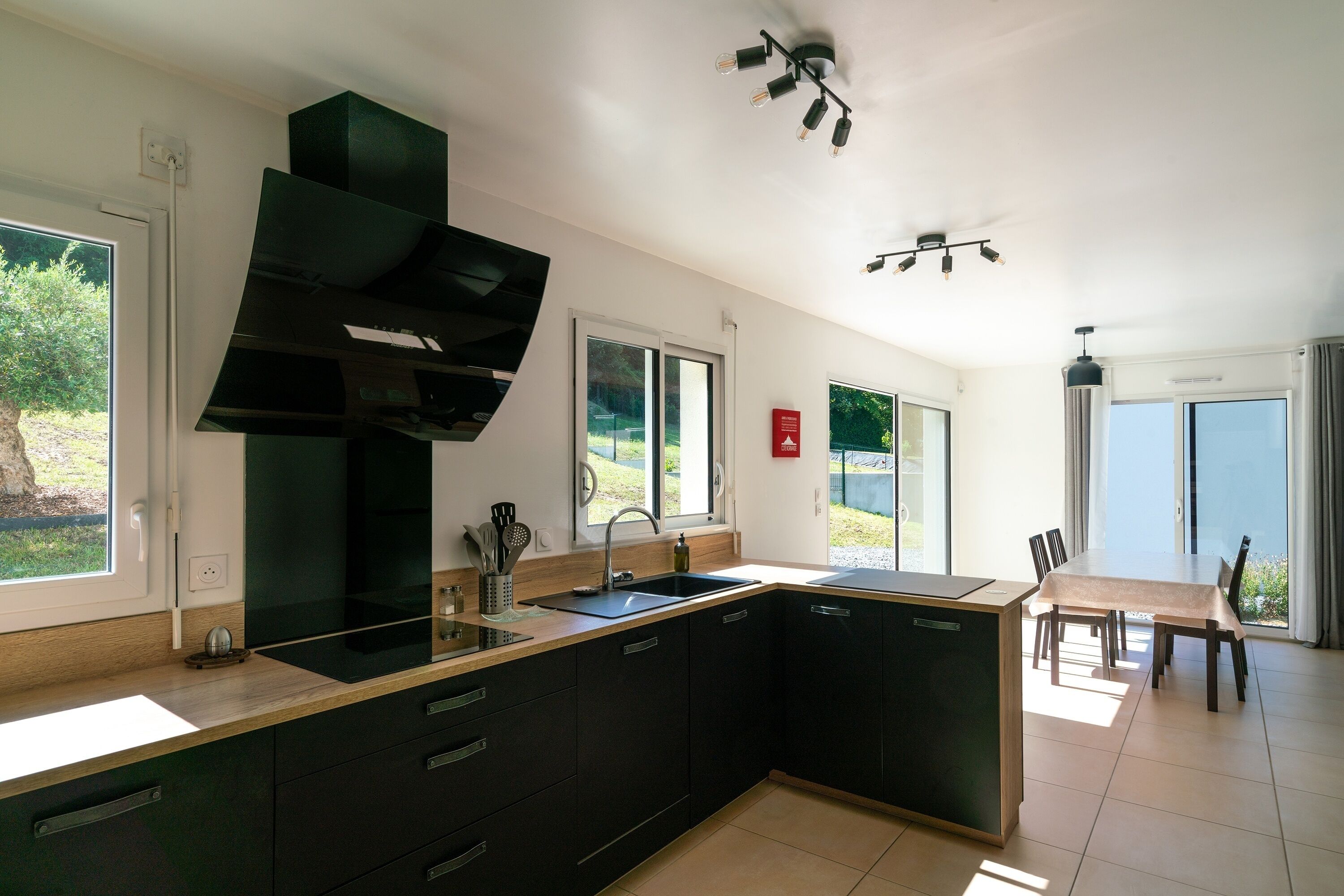 A modern kitchen with a large island, black cabinetry, and a built-in oven.