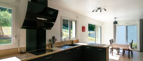 A modern kitchen with a large island, black cabinetry, and a built-in oven.