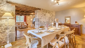 A dining area with a long table set for a meal, surrounded by wicker chairs. - Pierre Idyllique - Climatisée avec grand jardin (Saumont)