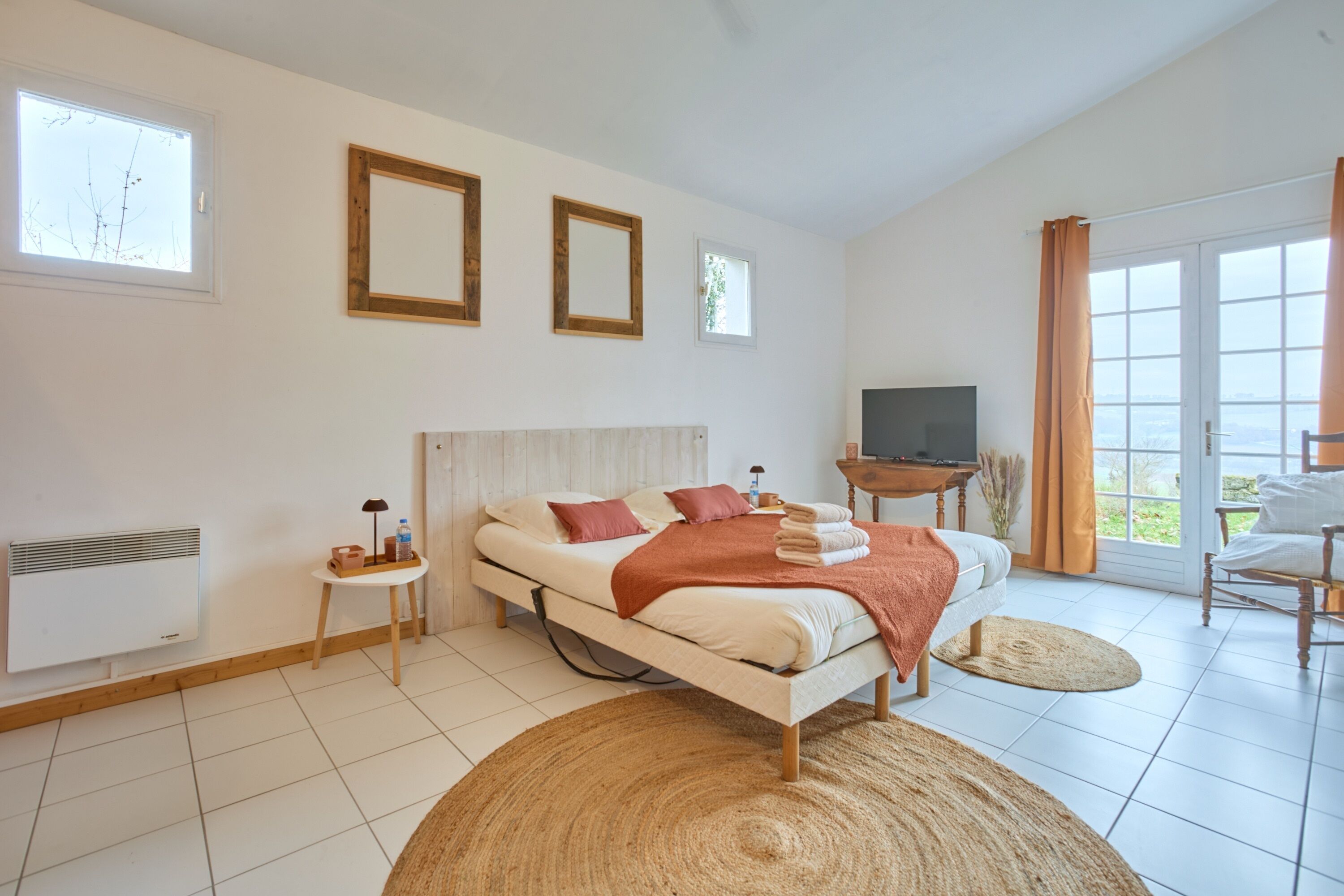 Une chambre à coucher avec un lit, une télévision, une petite table et une fenêtre.