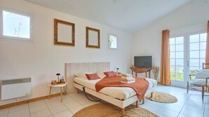 A bedroom with a bed, a television, a small table, and a window. - Pierre Idyllique - Climatisée avec grand jardin (Saumont)