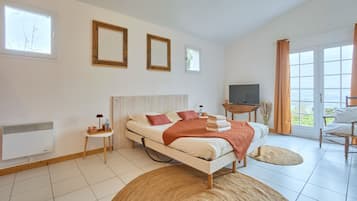 A bedroom with a bed, a television, a small table, and a window.