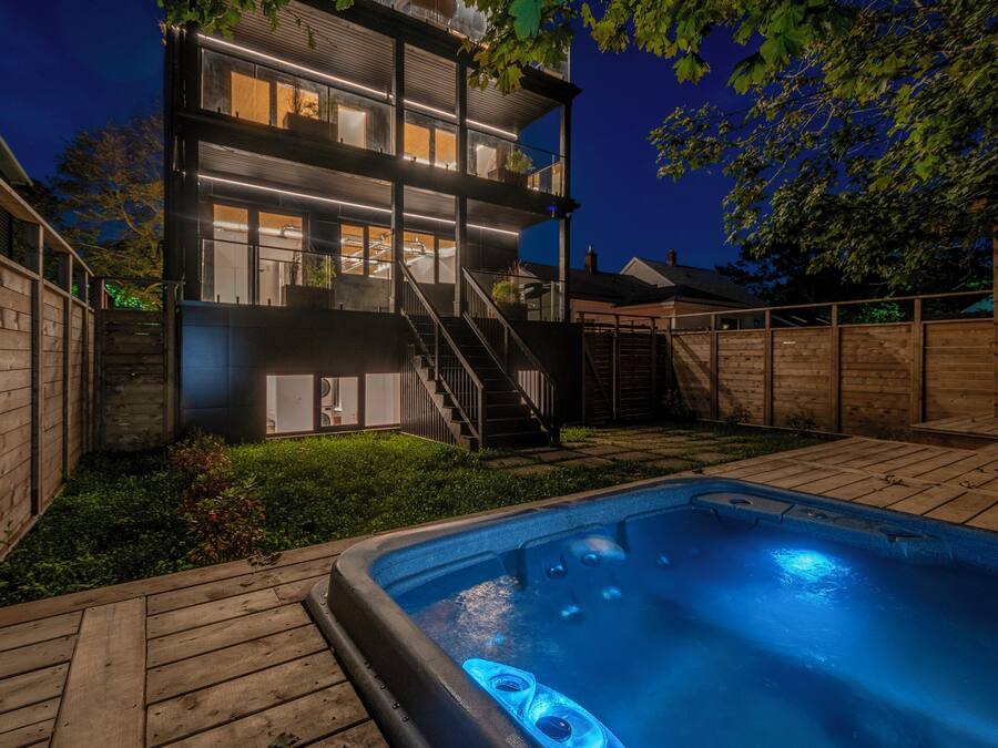 Un edificio moderno de dos pisos con jacuzzi en el patio trasero.