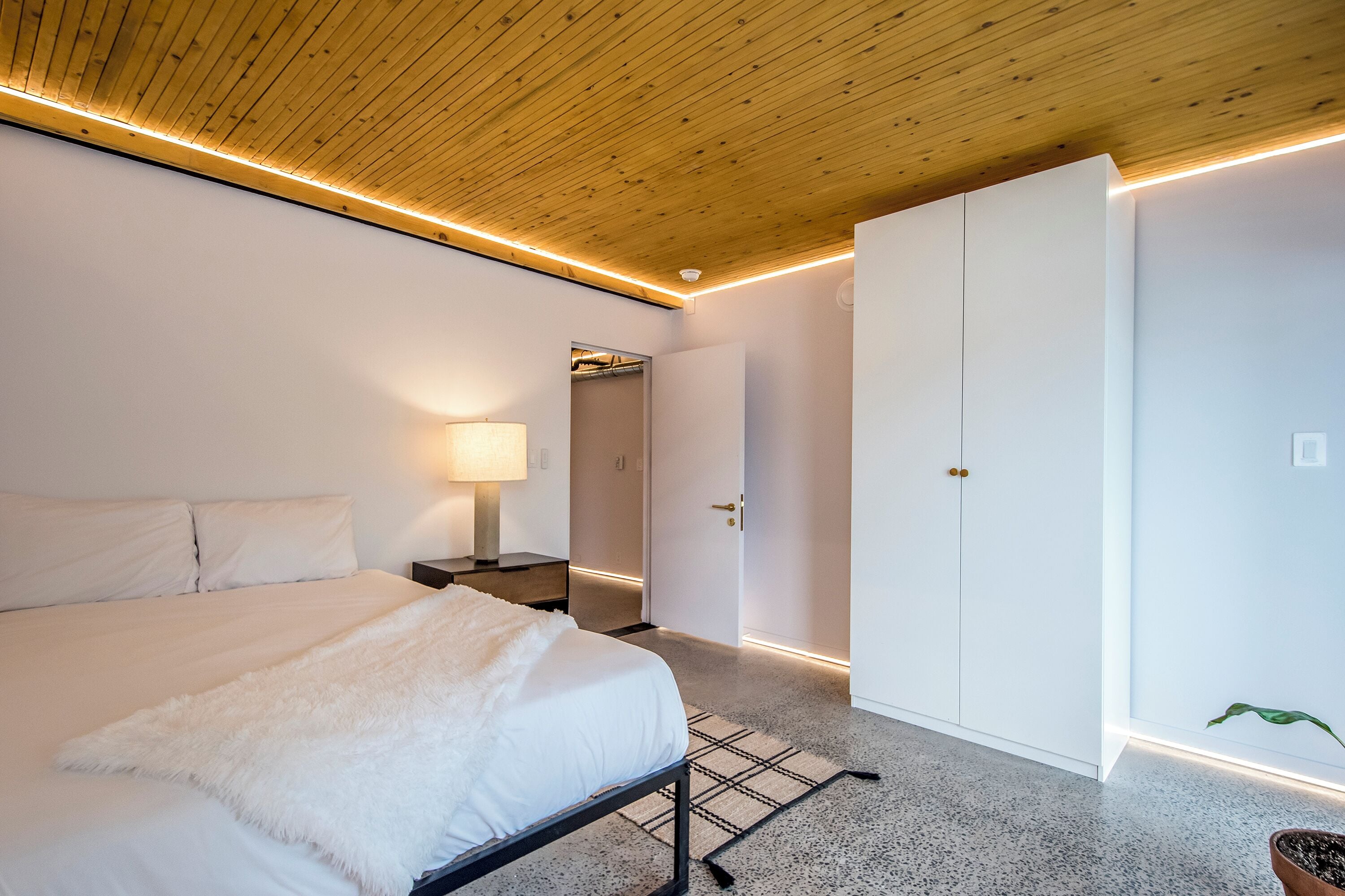A bedroom with a bed, bedside table, lamp, and a wardrobe.