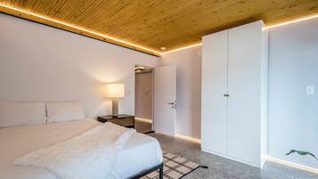 A bedroom with a bed, bedside table, lamp, and a wardrobe.