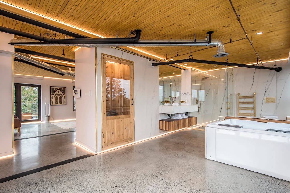 Un interior moderno con techo de madera, un área de spa con puerta de madera y un amplio mostrador de recepción blanco.