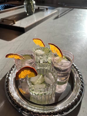 A tray with three glasses of a clear beverage, each garnished with orange slices and ice cubes.