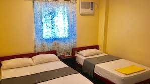 A room with two single beds, each with a pillow and a blanket. There is a nightstand with a picture frame between the beds. - CNC DIVE RESORT (Lapu-Lapu)