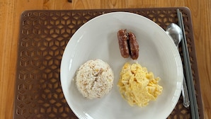 Two plates with rice and scrambled eggs on a wooden table with a patterned placemat. - CNC DIVE RESORT (Lapu-Lapu)