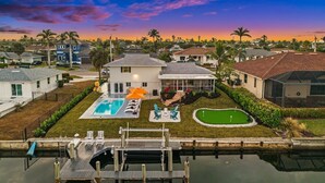 Zona residenziale con piscina, un piccolo campo da golf e un pontile che si affaccia su un'area d'acqua.