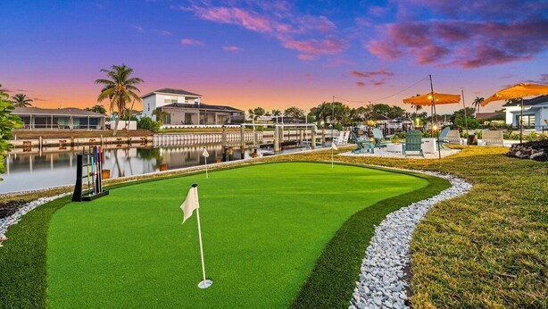 Un campo da golf con una bandiera, uno stagno e case sullo sfondo.