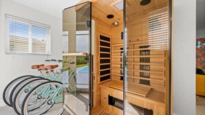 A sauna with a glass door, a bicycle, and a view of the outdoors.