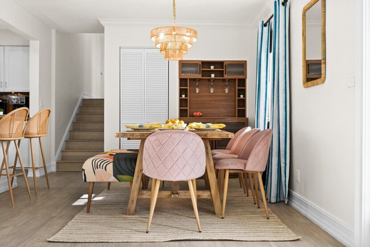 Un comedor con mesa de madera, sillas y una araña.