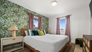 Una camera da letto con un letto, comodini, una cassettiera e una finestra con tende.