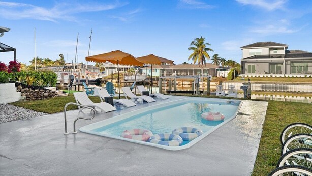 A swimming pool with lounge chairs, umbrellas, and a clear sky.