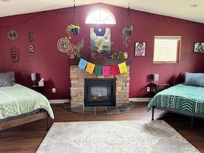 A room with a fireplace, two beds, a stone wall, and various wall decorations. - Relax near CMU and Casino with hot tub and fireplace (Mount Pleasant)