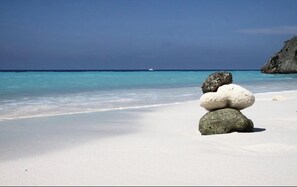 Une plage de sable blanc avec un amas de rochers.
