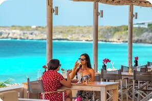 A dining area with a view of the ocean, wooden tables, and chairs.