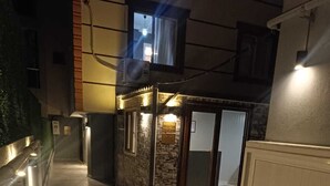 Een hal met een receptiehoek, voorzien van een stenen muur en glazen deuren, die leidt naar een kamer.