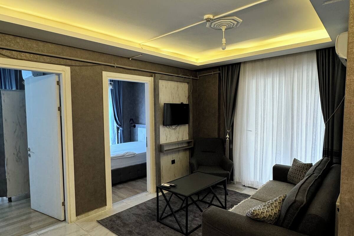 A modern living room with a sofa, coffee table, and a TV mounted on the wall. There is a sliding door leading to another room.